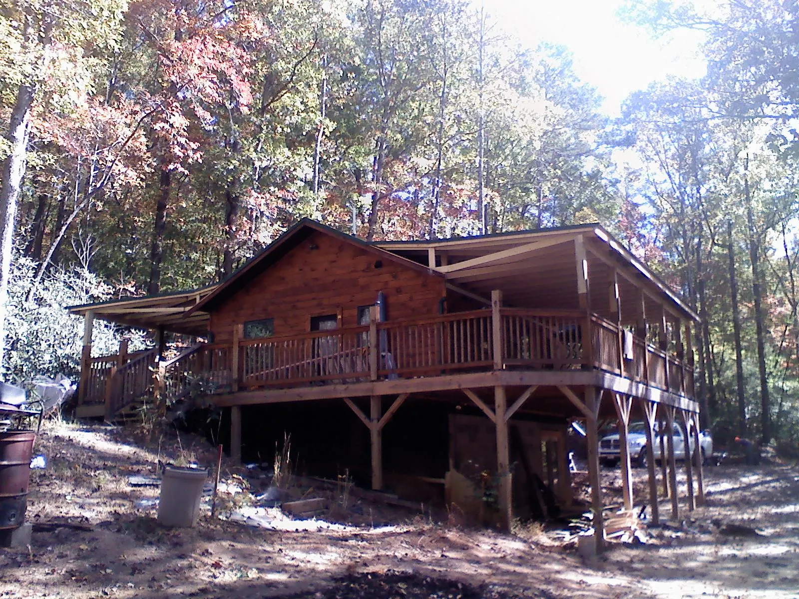 Log cabin with a wraparound porch and metal roof in the fall in Oakfield