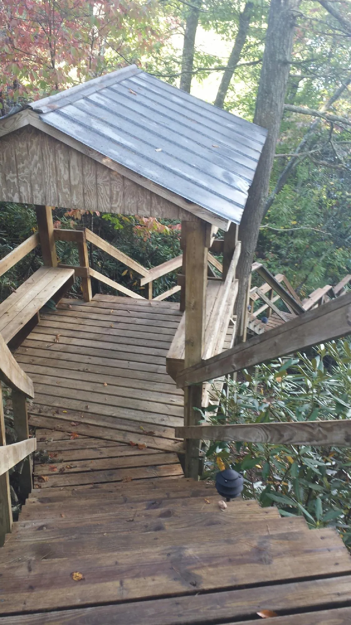 Metal roofed shelter over wooden steps on a wooded walkway — Skylight Repair & Installation work by our crew in Oakfield